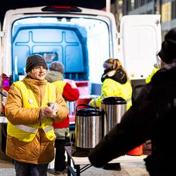 Eine ehrenamtliche Helferin überreicht bei frostigen Temperaturen am Kältebus der Caritas einen Becher Kaffee.