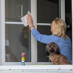 Eine Frau putzt die Fenster ihrer Wohnung