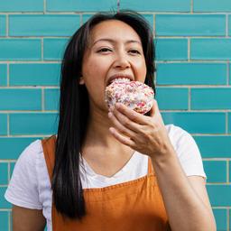 Junge Frau beißt in einen Donut.